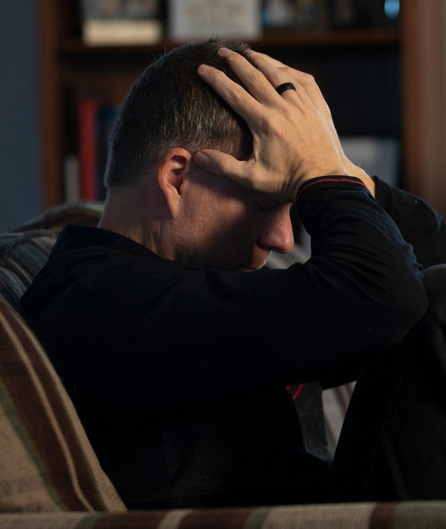 Photo by Malachi Cowie a man sitting on a couch holding his head in his hands